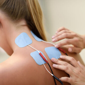 Electro stimulation in physical therapy to a young woman. Medical check at the shoulder in a physiotherapy center.